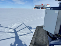 Een door Bachmann gebouwd Structural Health Management systeem aan het werk in de schaduw van de verticale windturbine op Neumayer Station III in Antarctica. De componenten in de grijze doos rechts en andere componenten van het systeem zijn bestand tegen temperaturenpieken tot -40 °C.'