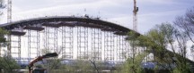 12.000 ton hydraulische kracht buigt de betonnen constructie van de Derde Milleniumbrug in Zaragoza, om het laatste deel van de boog te kunnen gieten en sluiten als kroon op het werk.'