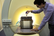 TU/e-promovendus Tim Donkers bij de MRI-scanner van het nieuwe Darcylab. Op de slede van de scanner staat de houder waarin staafvormige monsters gaan. De houder is voorzien van koeling en verwarming om de juiste omstandigheden te creëren. (Foto: TU/e)'