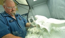 Ford-medewerker Mark Smith werkt aan de nabehandeling van een 3D-geprint ventilatie-onderdeel.'